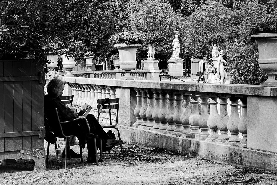 Moteris pavėsyje skaitanti knygą Liuksemburgo soduose Paryžiuje