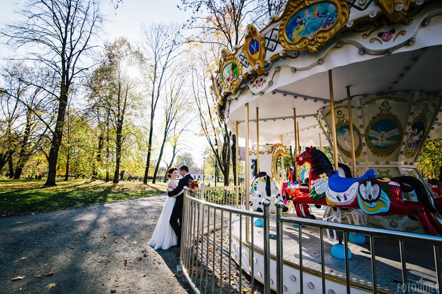 Jaunavedžiai atsirėmę į karuselės apsauginę tvorelę Bernardinų sode Vilniuje
