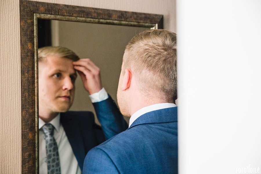 Jaunikis taisosi savo šukuoseną žiūredamas į veidrodį